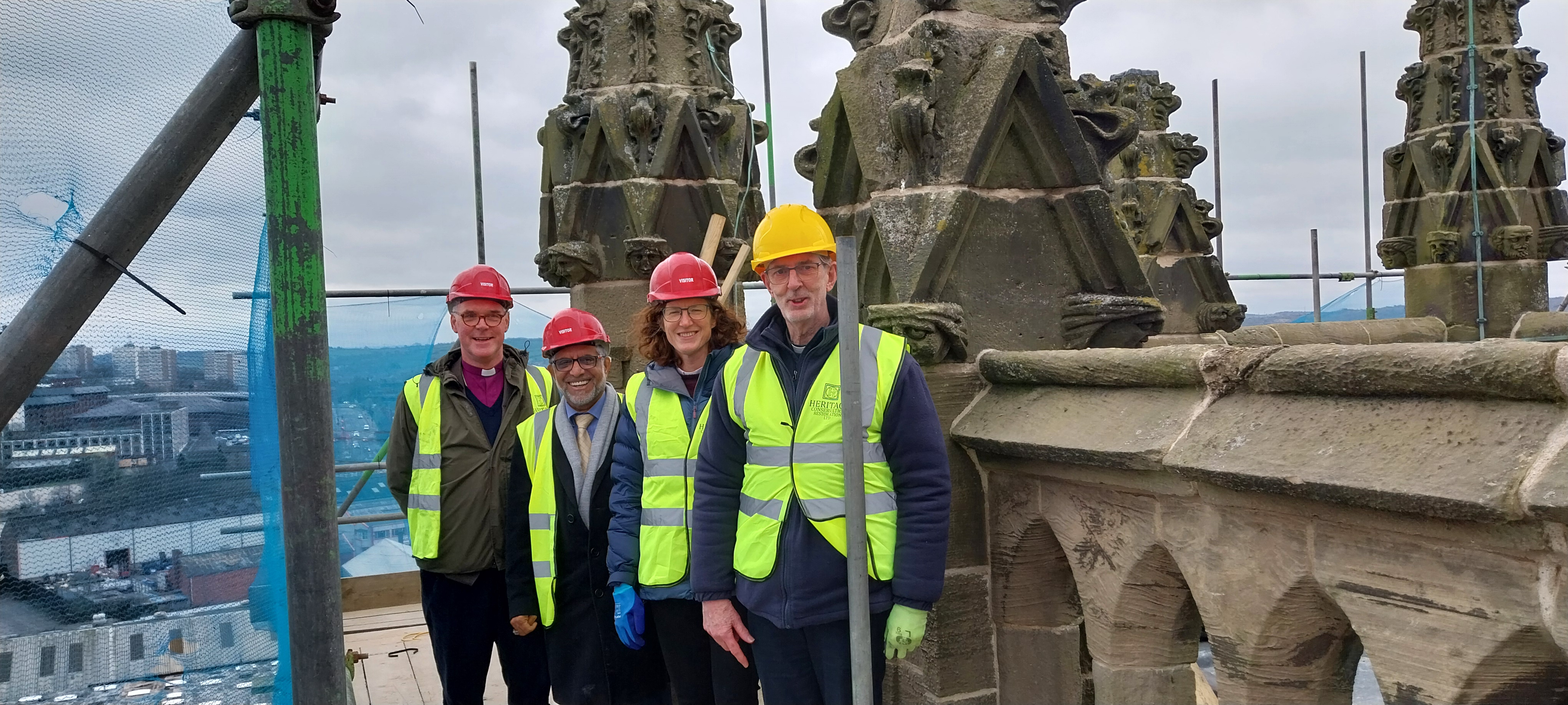 Rt Revd Matthew Parker, Councillor Majid Khan, The Ven Megan Smith, Revd Phillip Jones on the scaffolding around the tower of St Mark's church, Stoke, with the city skyline behind them