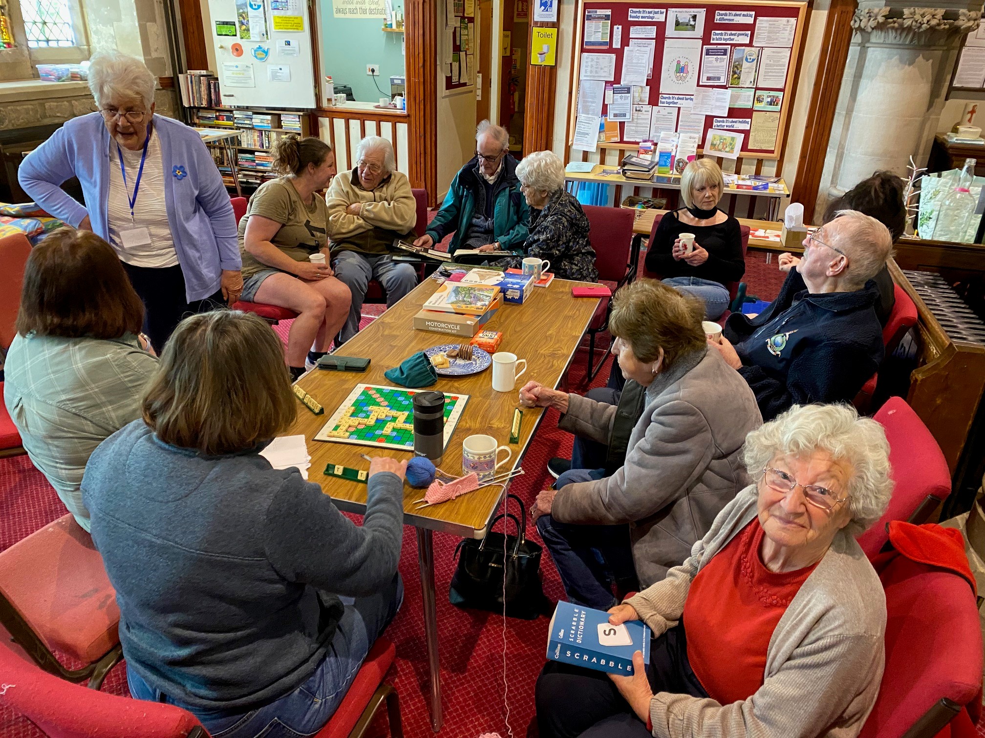 a dozen people sat round a table playing board games